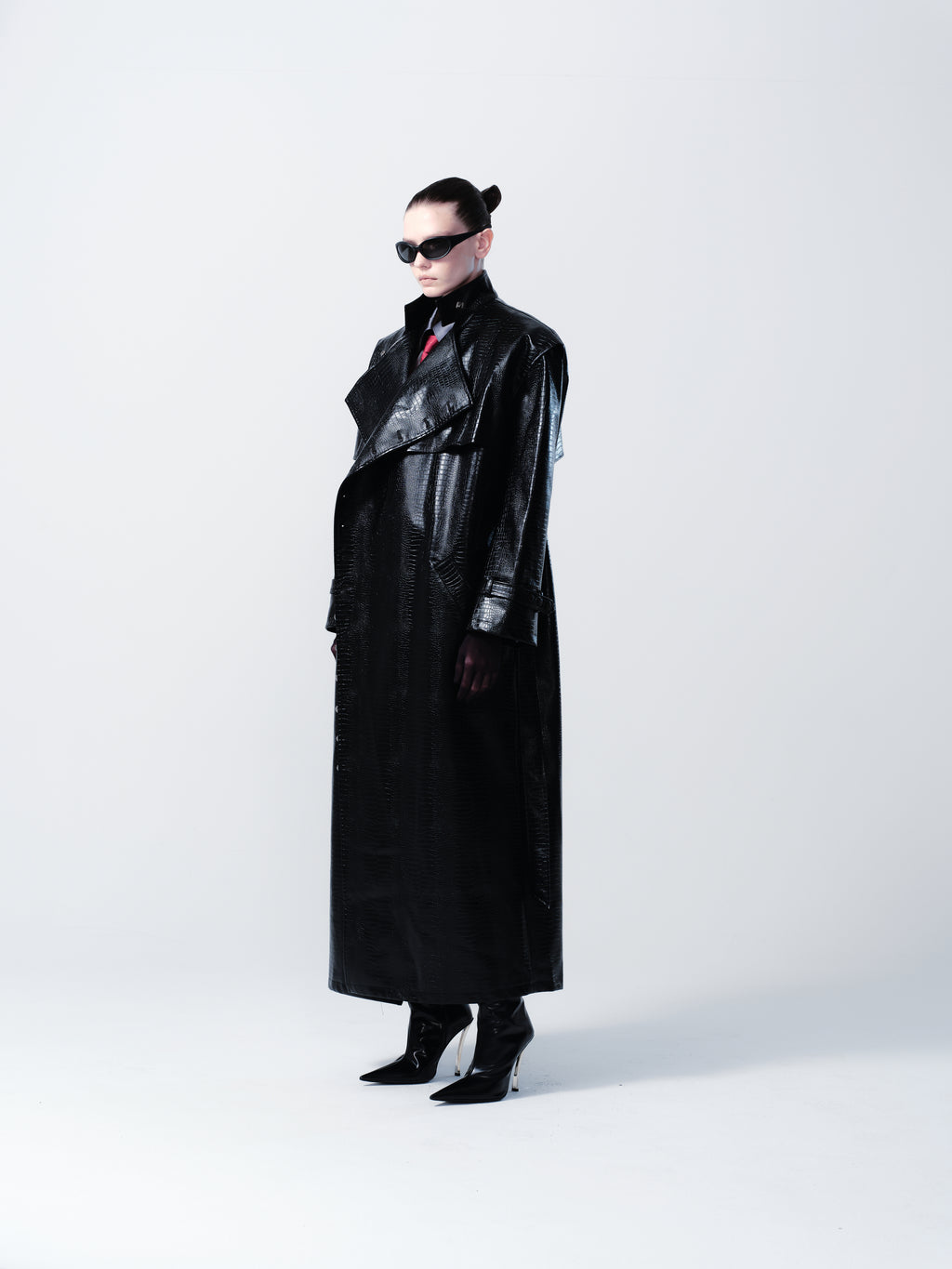 Person wearing a black leather outfit with sunglasses on a white background