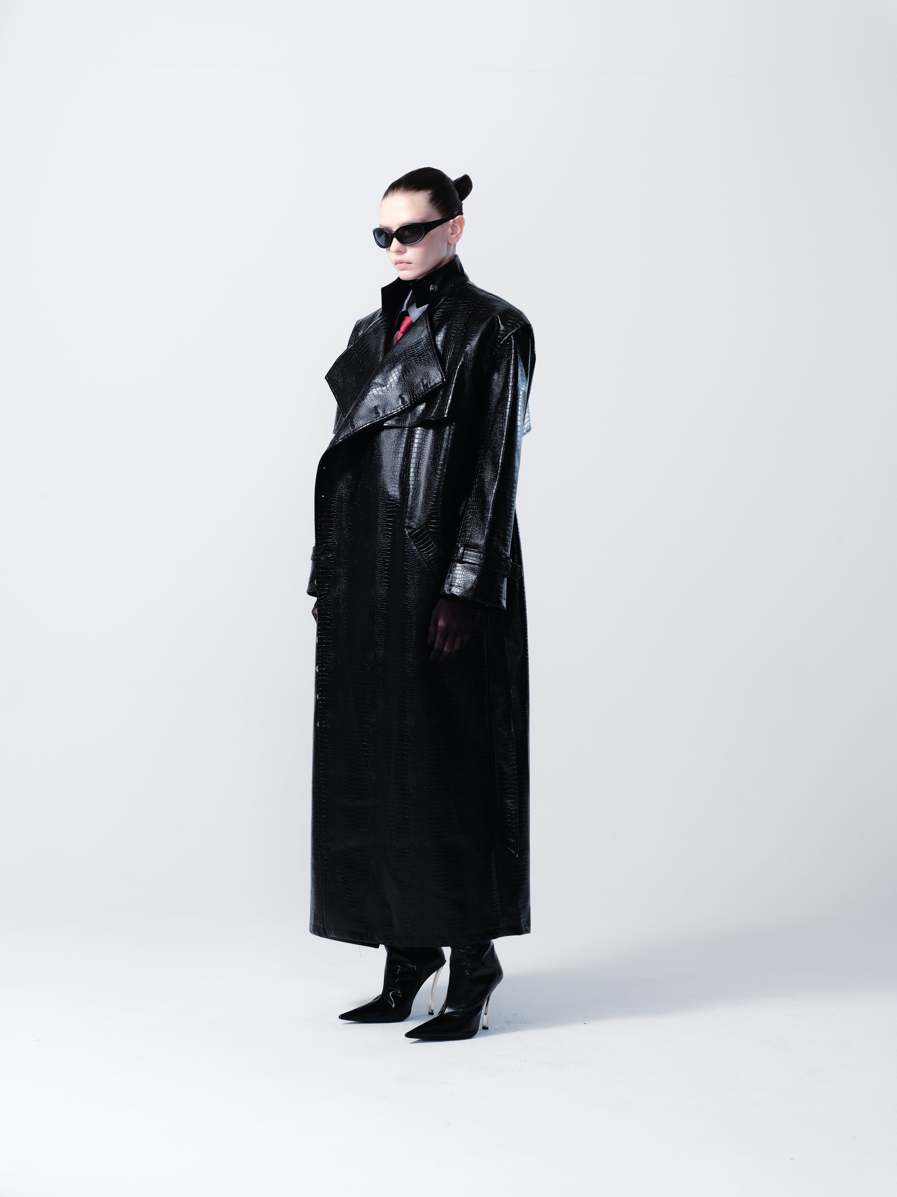 Person wearing a black leather outfit with sunglasses on a white background